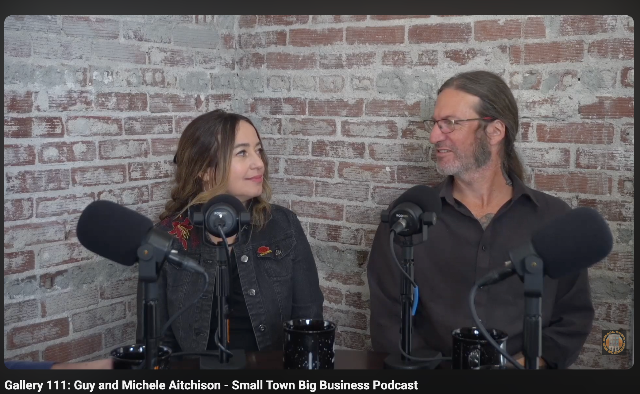 Load video: n this episode of Small Town Big Business, hosts Jennifer Olson and Russ Williams speak with renowned artists Guy and Michelle Aitchison about their journey from Chicago to Southern Illinois, where they have established Hyperspace Studios. The couple discusses their multifaceted artistic careers, including tattooing, painting, and music, and their contributions to the local art scene. They share their vision for revitalizing Marion by opening Gallery One Eleven, an art gallery and Airbnb space. The conversation explores the changing acceptance of tattoos, the resurgence of downtown Marion, and the significance of community engagement and social currency in fostering an arts scene. The episode underscores the importance of perseverance and adaptation in pursuing creative enterprises.